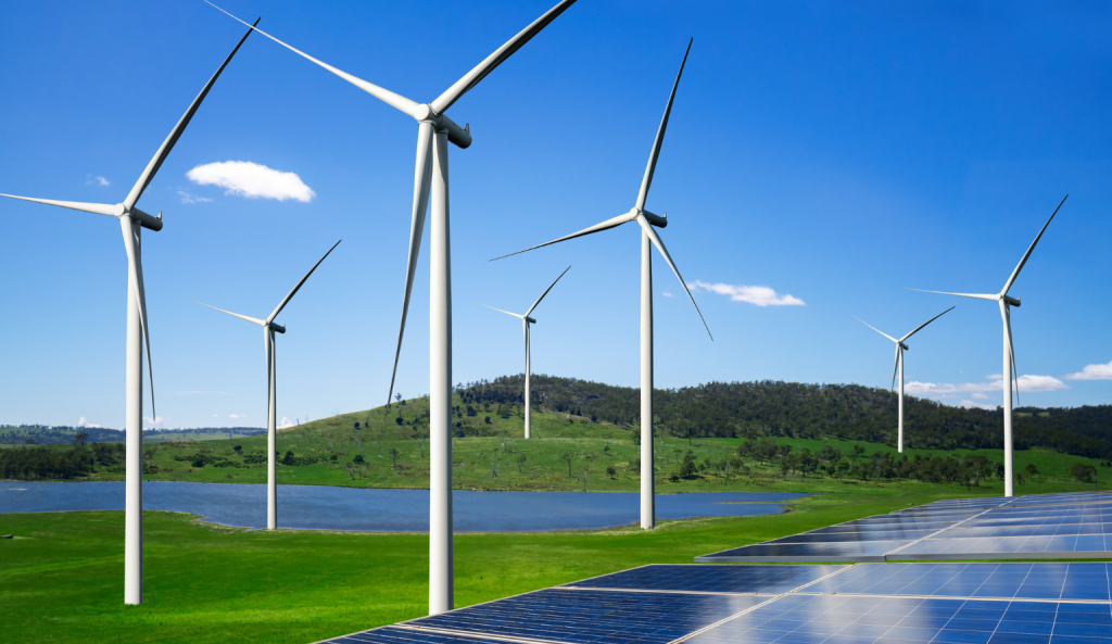 Wind turbines and solar panels generating renewable energy in a green landscape near a lake