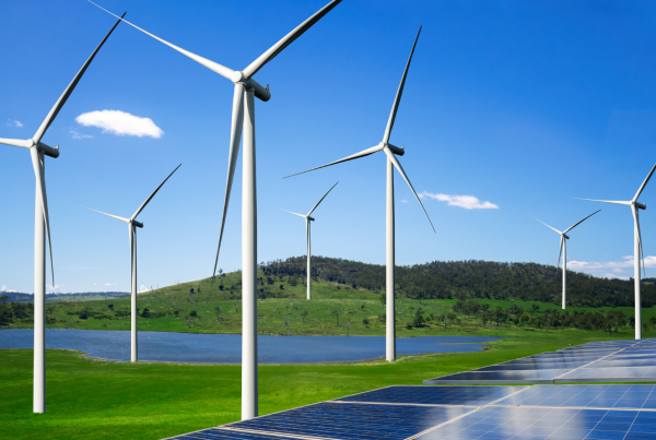 Wind turbines and solar panels generating renewable energy in a green landscape near a lake
