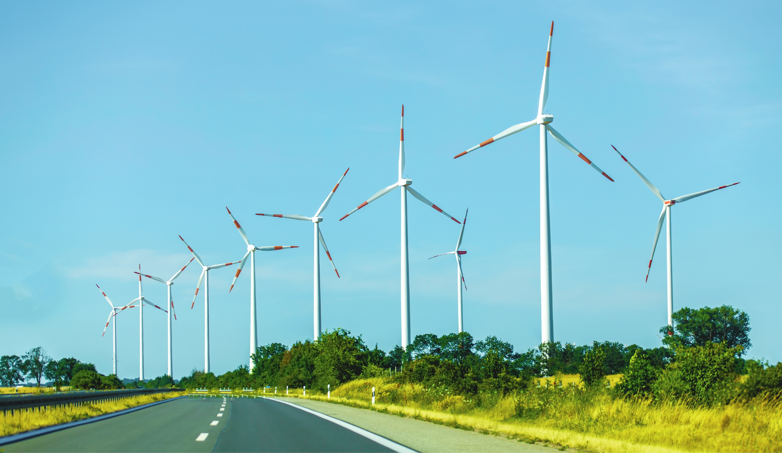 Wind turbines along a highway generating clean renewable energy in a rural landscape