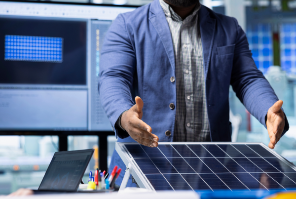 Engineer explaining a solar panel system in a lab with digital monitoring screens