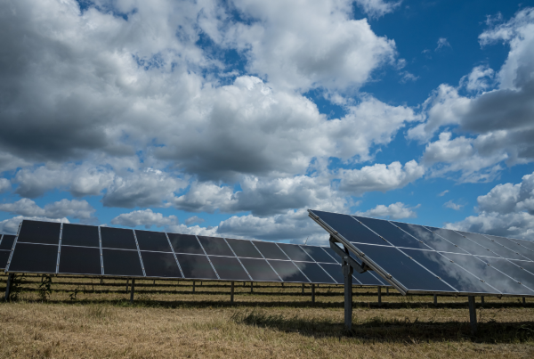 Solar panels in an open field generating renewable energy under a partly cloudy sky