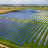 Large-scale solar power plant with rows of photovoltaic panels installed across green farmland in India